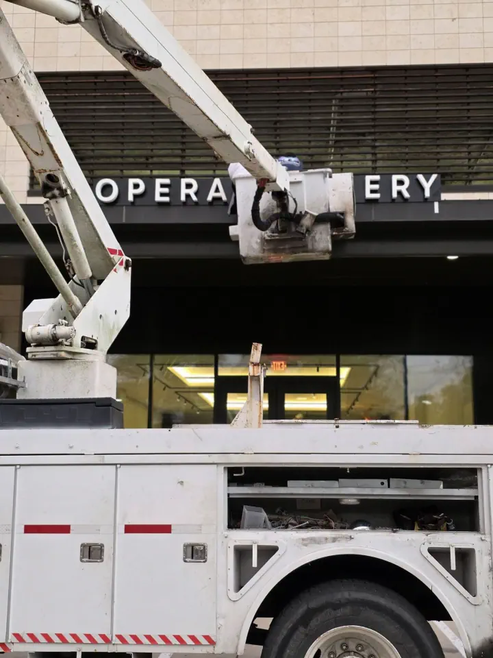 Crew installing OPERA GALLERY letters above a storefront