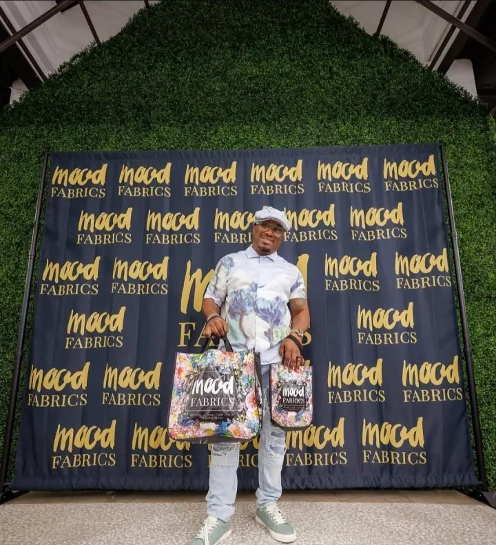 Person standing before a Mood Fabrics branded photo backdrop