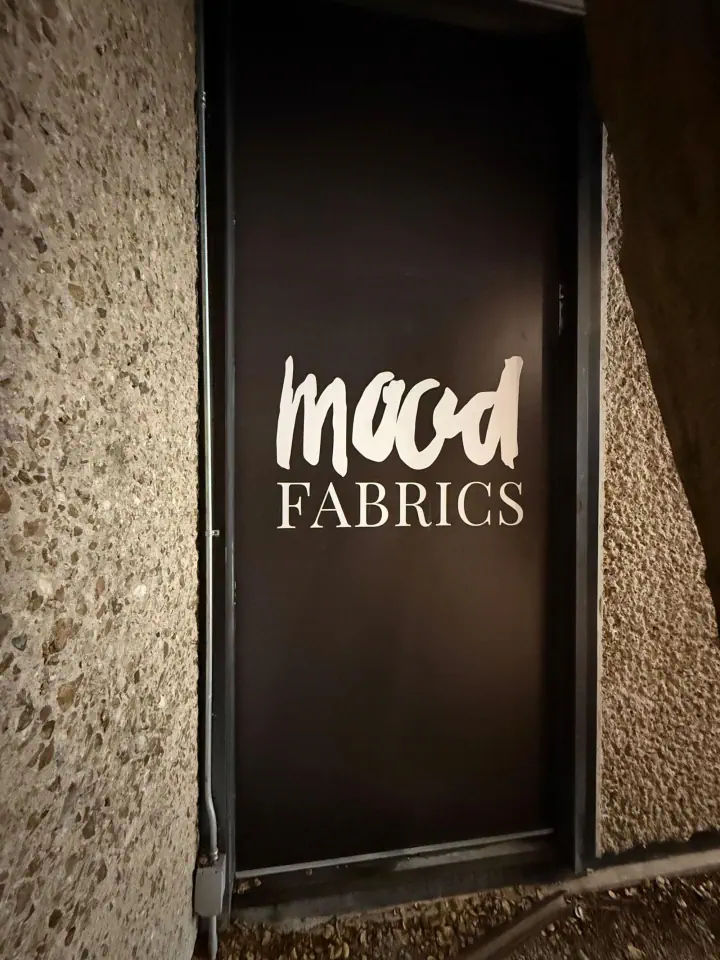 Mood Fabrics illuminated sign in a storefront window