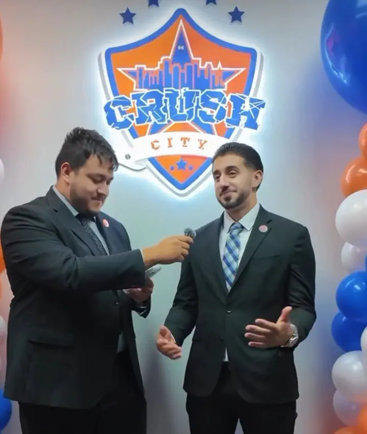 Two people standing before a lit Crush City wall logo