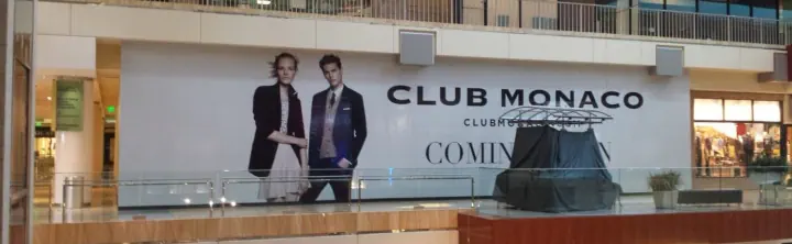 Club Monaco storefront graphics across a shopping mall wall