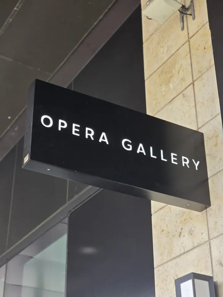 OPERA GALLERY projecting blade sign mounted on an exterior wall